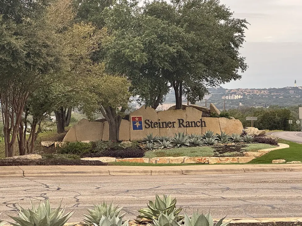 Steiner Ranch entrance monument surrounded by trees and native landscaping
