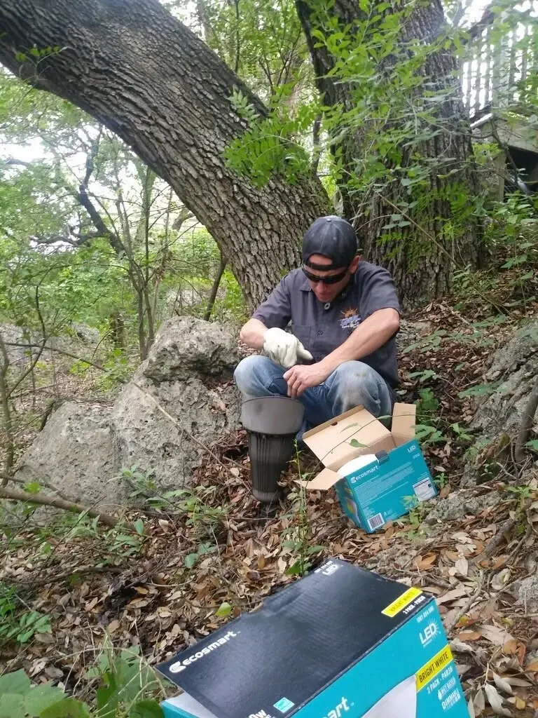 A person handling equipment beside a large tree and open boxes.