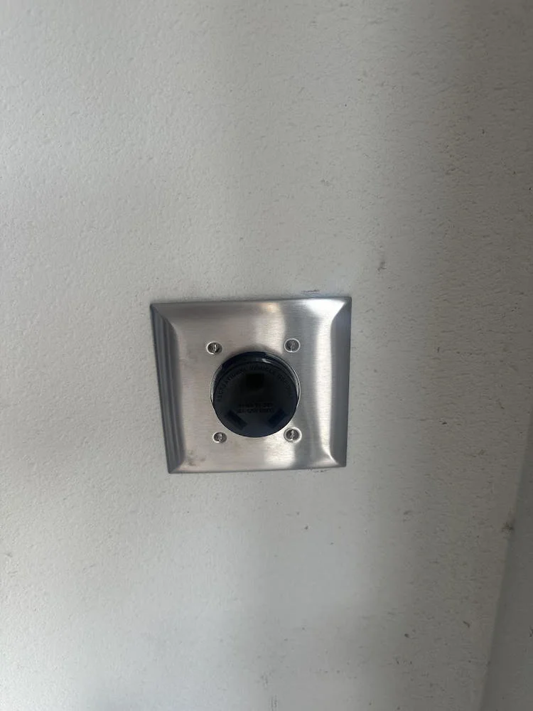 Round power receptacle with a stainless steel wall plate.