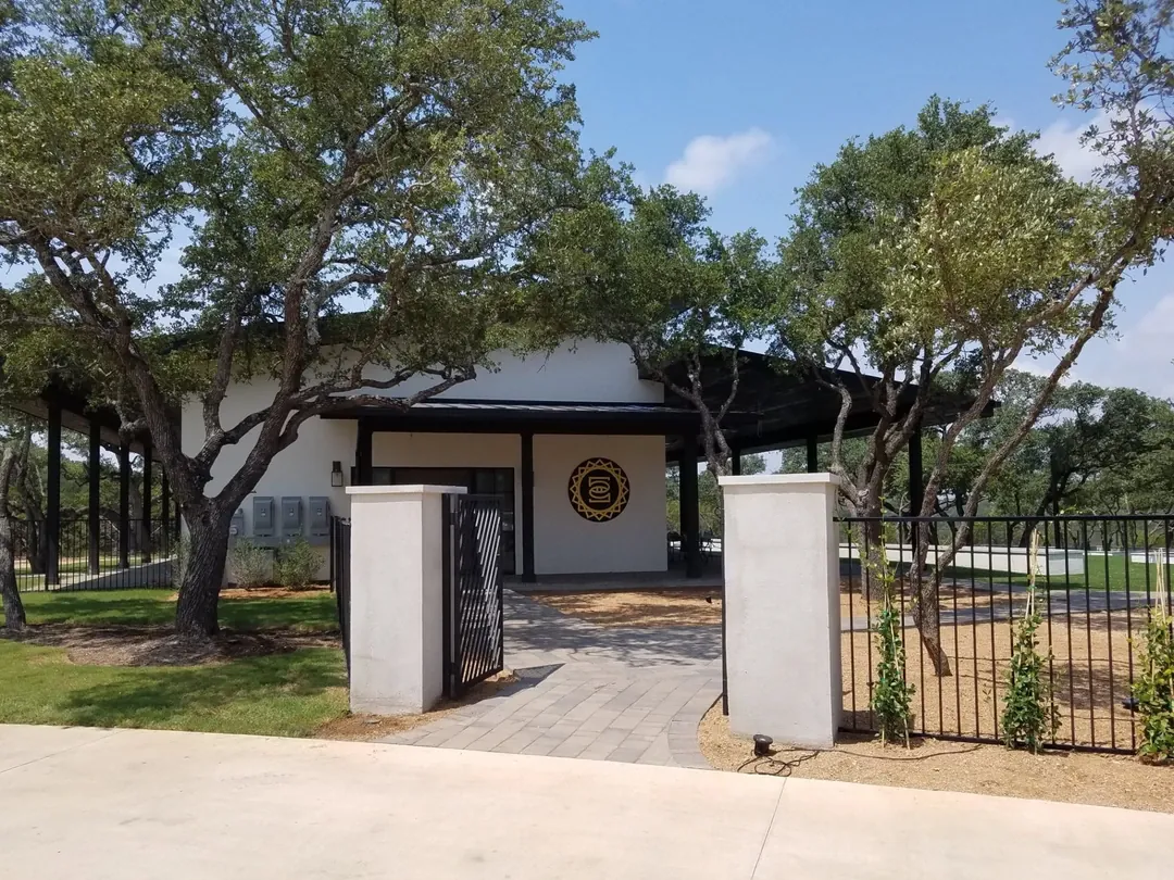 Gated entrance to a small pavilion shaded by trees.