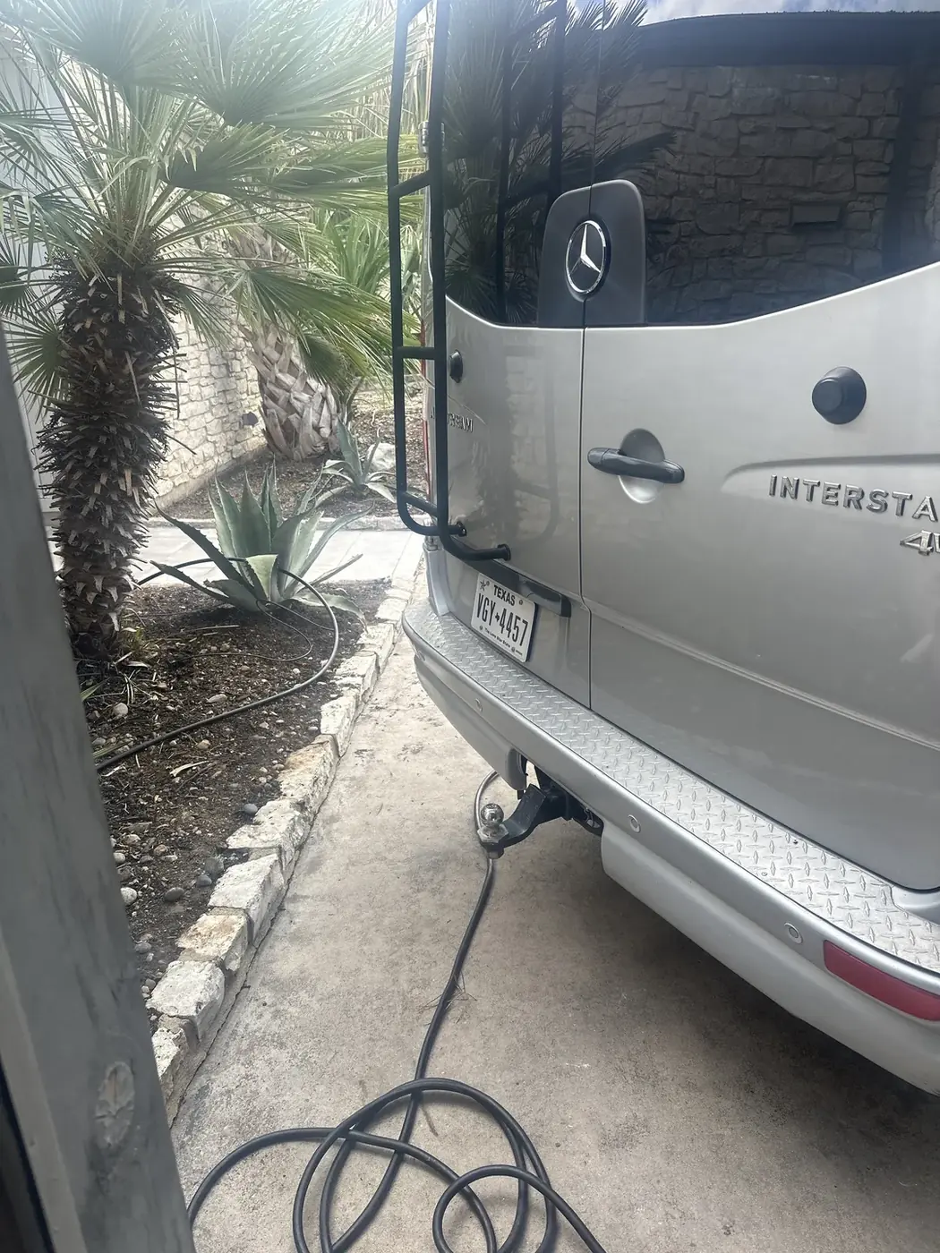 Camper van connected to an electrical cable in a driveway.