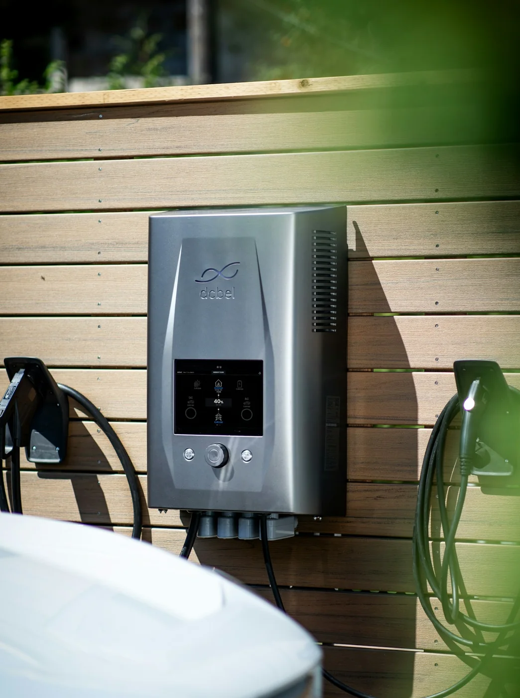 Wall-mounted EV charging equipment with two charging cables on a timber wall