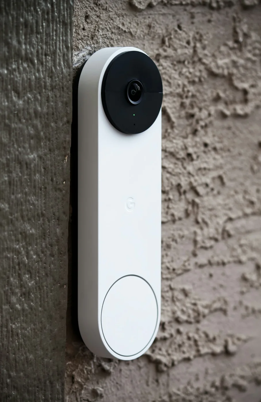 White video doorbell with a black camera lens mounted on an exterior wall
